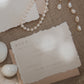 wedding rsvp card with blind letterpress leaf vine printed on handmade cotton paper and styled with a light blush return envelope 