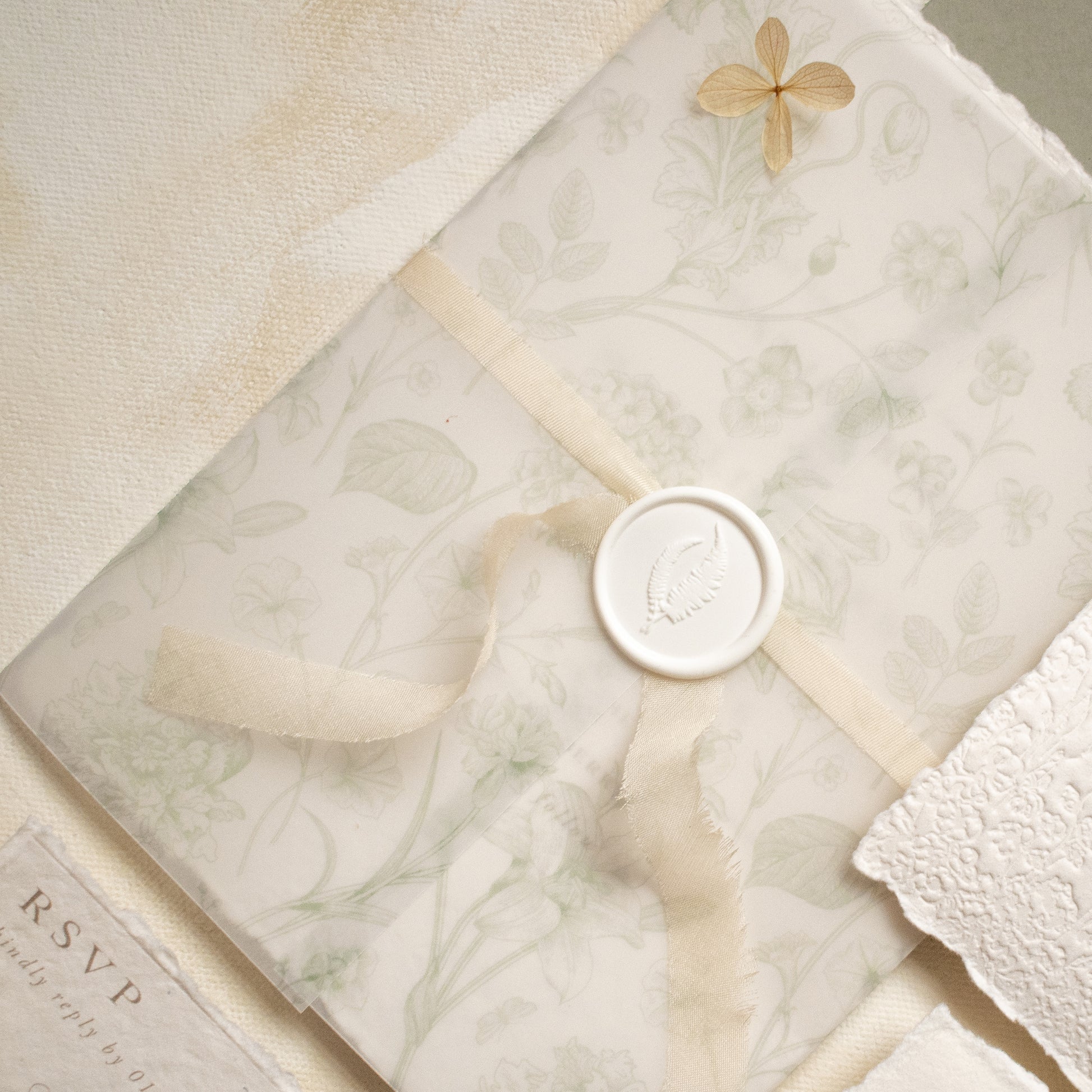 sage green floral vellum wrap with hand dyed silk ivory ribbon and white wax seal for wedding invitations