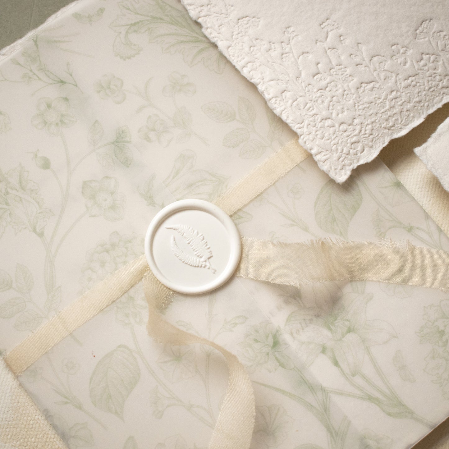 sage green floral vellum wrap with hand dyed silk ivory ribbon and white wax seal for wedding invitations