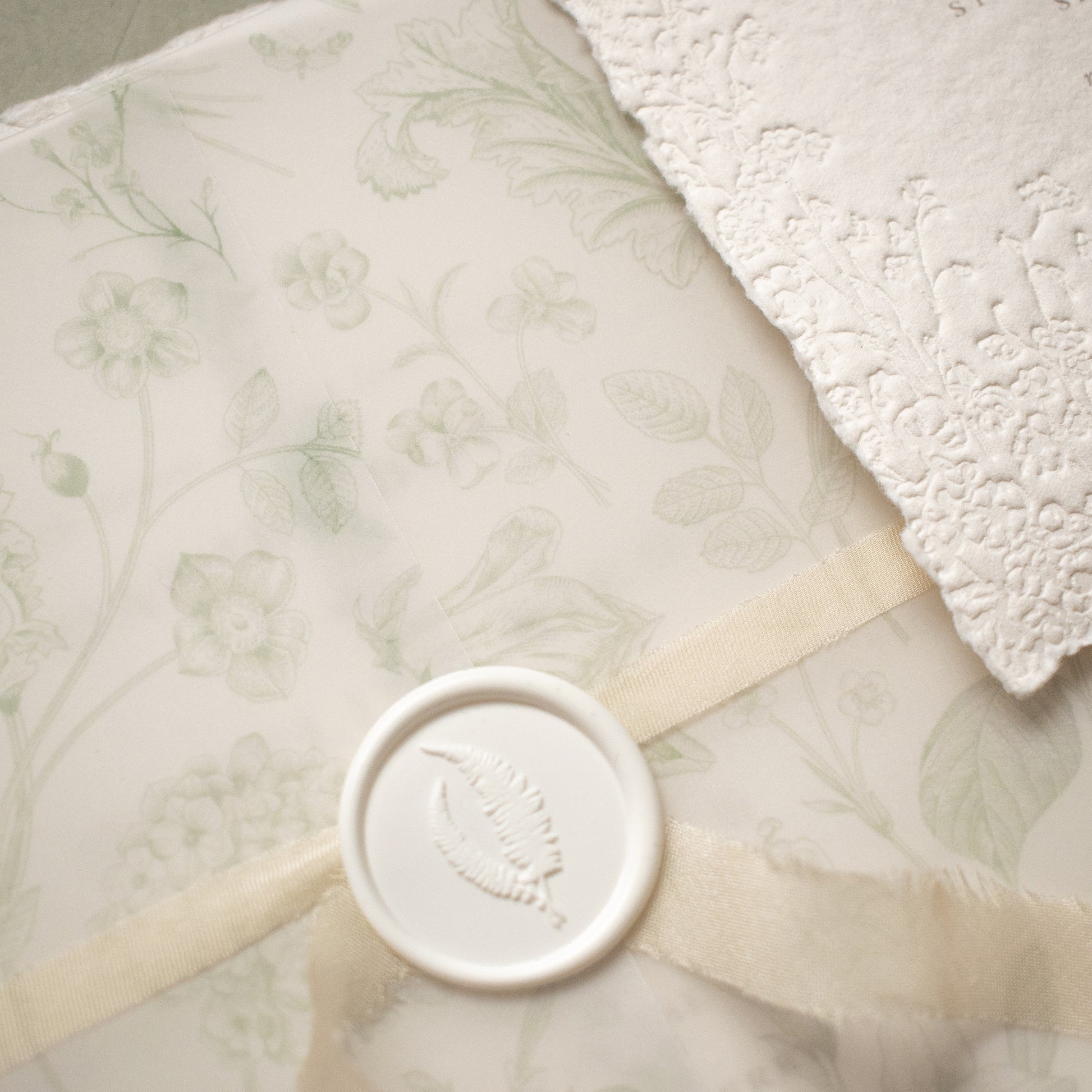 sage green floral vellum wrap with hand dyed silk ivory ribbon and white wax seal for wedding invitations